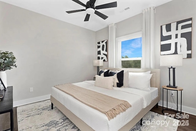 bedroom with a ceiling fan, baseboards, visible vents, and wood finished floors