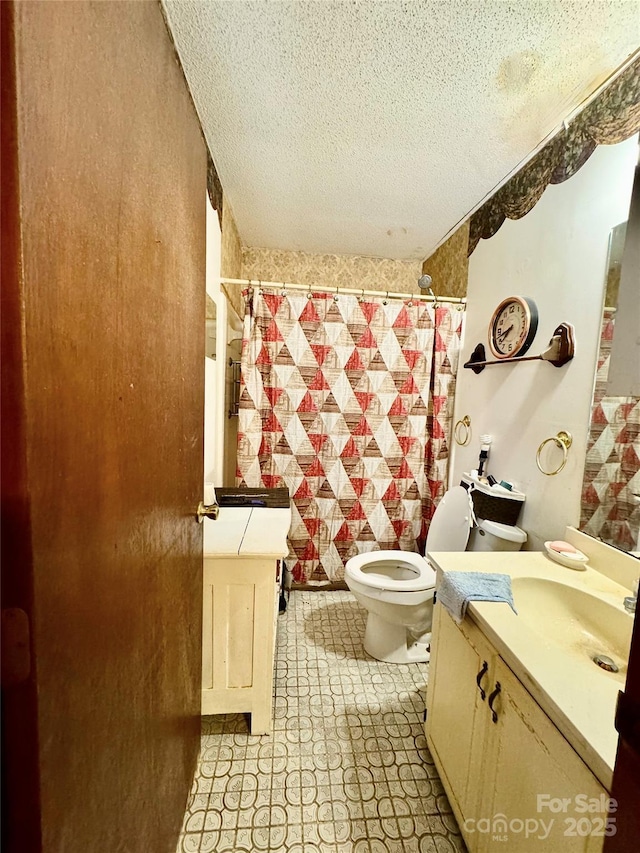 bathroom with vanity, toilet, and a textured ceiling