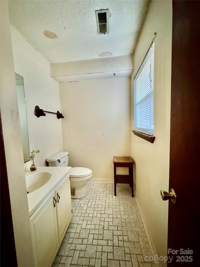 bathroom featuring vanity, toilet, and a textured ceiling