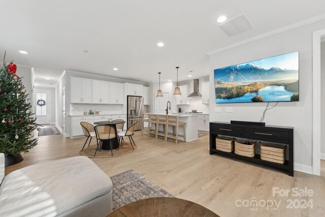 living room with crown molding, sink, and light hardwood / wood-style floors