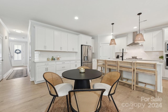 kitchen with pendant lighting, white cabinetry, wall chimney range hood, and stainless steel appliances