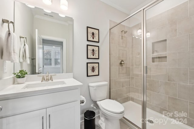 bathroom featuring vanity, toilet, a shower with shower door, and crown molding