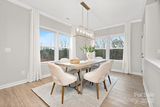 dining space featuring a notable chandelier, crown molding, and light wood-type flooring