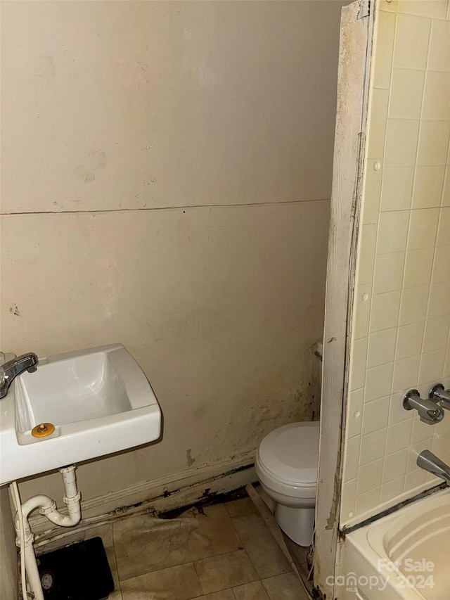 bathroom featuring tile patterned floors, a bath, toilet, and sink