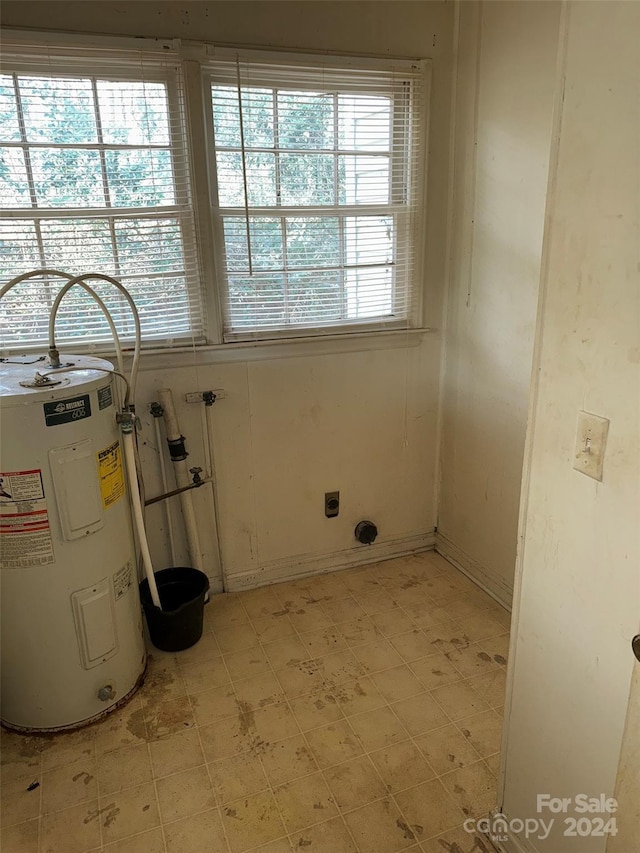 clothes washing area with water heater and plenty of natural light