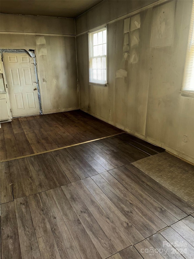 unfurnished room with wood walls and wood-type flooring