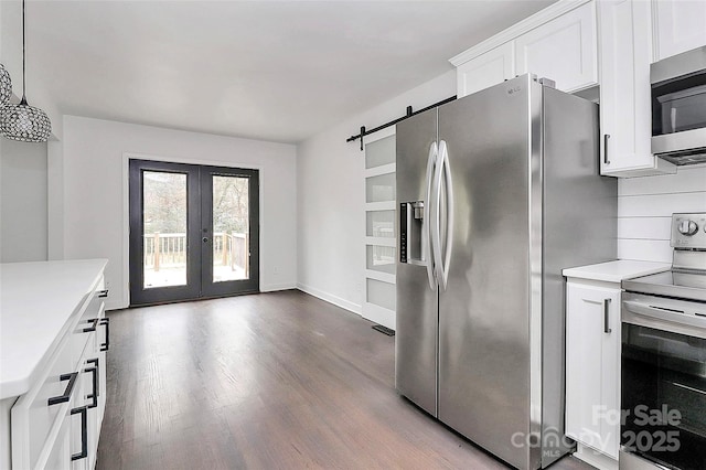 kitchen featuring a barn door, white cabinetry, hanging light fixtures, stainless steel appliances, and french doors