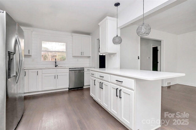 kitchen featuring decorative light fixtures, stainless steel appliances, and white cabinetry