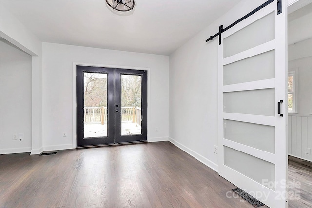 interior space featuring dark hardwood / wood-style floors, built in features, french doors, and a barn door