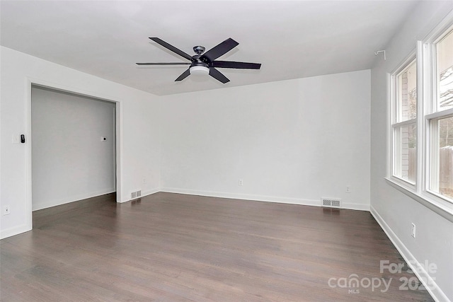 empty room featuring ceiling fan, a healthy amount of sunlight, and dark hardwood / wood-style floors