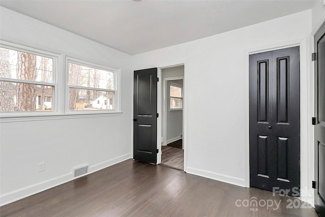 unfurnished bedroom featuring dark hardwood / wood-style floors and a closet