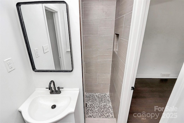 bathroom with a tile shower and sink