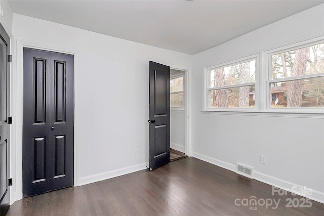 unfurnished bedroom with a closet and dark hardwood / wood-style floors