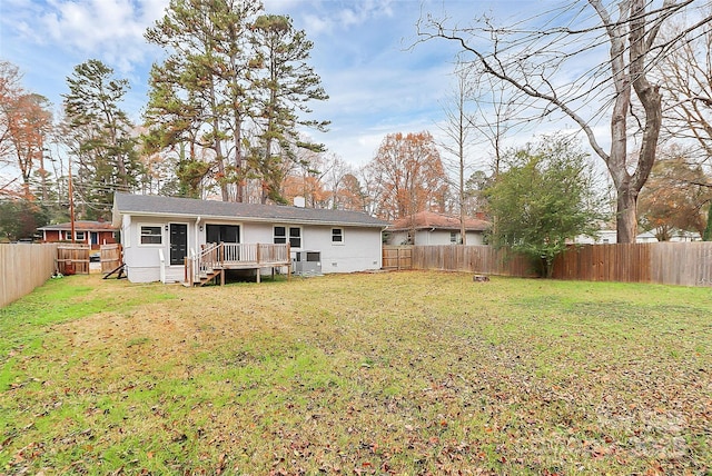 back of property with a wooden deck, cooling unit, and a lawn