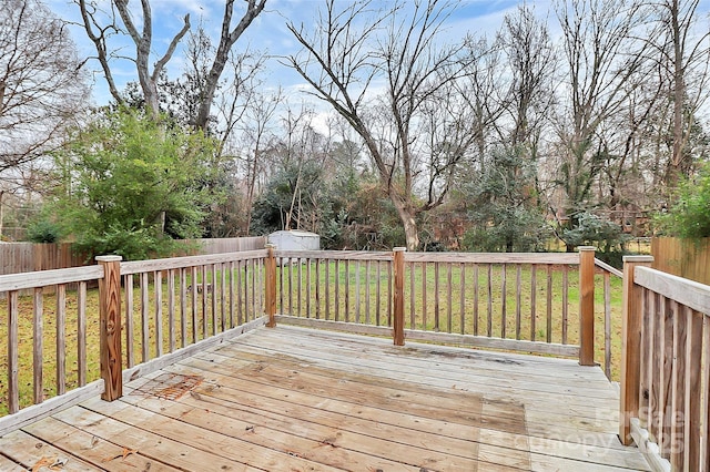 wooden terrace featuring a lawn and a storage shed