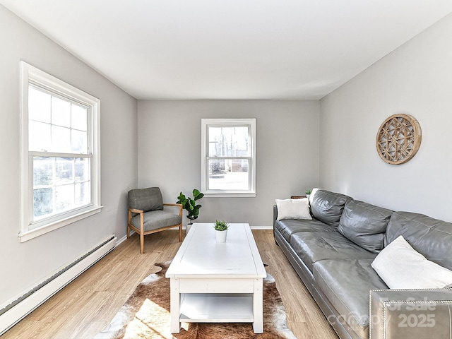 living room with a baseboard heating unit, a wealth of natural light, and light hardwood / wood-style floors