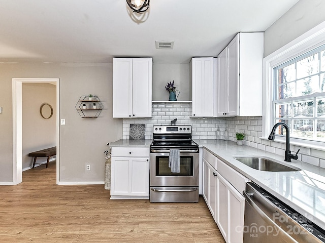 kitchen featuring white cabinetry, appliances with stainless steel finishes, sink, and light wood-type flooring