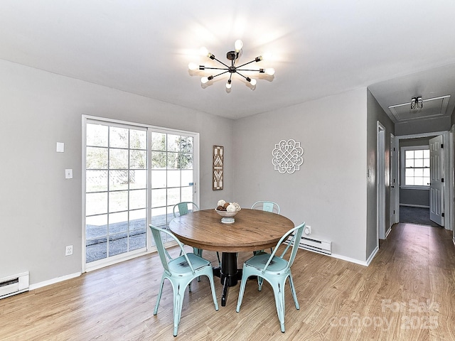 dining space featuring a baseboard heating unit, a chandelier, and light hardwood / wood-style floors