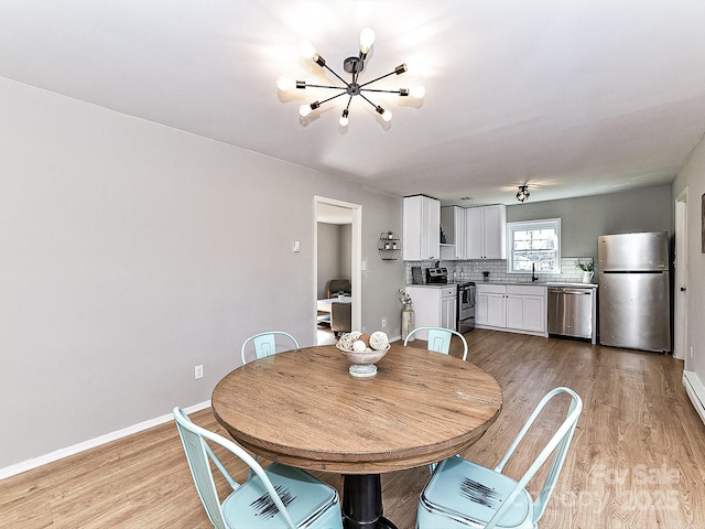 dining space with sink, an inviting chandelier, and light wood-type flooring