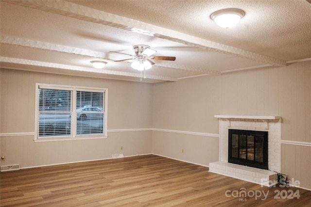 unfurnished living room featuring hardwood / wood-style flooring, ceiling fan, a textured ceiling, and a brick fireplace