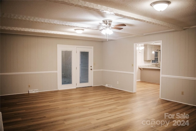 unfurnished room featuring ceiling fan, wood walls, wood-type flooring, and a textured ceiling