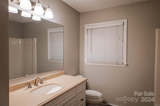 bathroom featuring vanity, toilet, and walk in shower