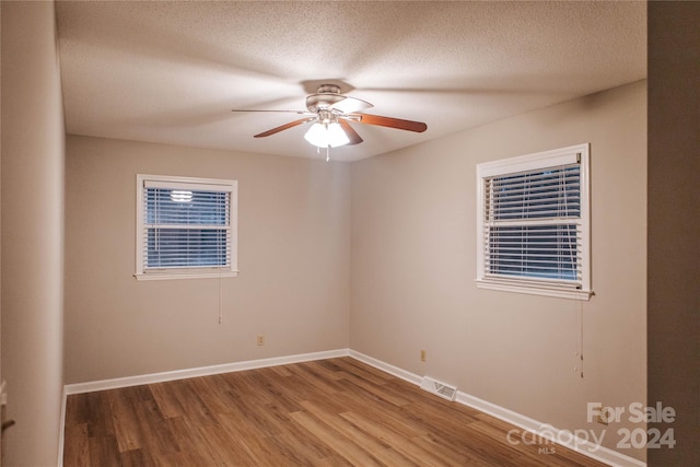 empty room featuring ceiling fan, wood-type flooring, and a textured ceiling