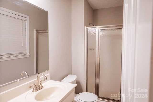 bathroom with vanity, toilet, a shower with door, and a textured ceiling