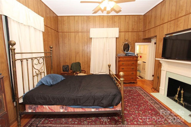 bedroom with ceiling fan, wood walls, and hardwood / wood-style flooring