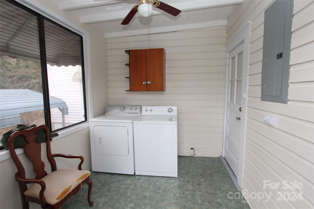 laundry area with ceiling fan, cabinets, electric panel, wooden walls, and washer and clothes dryer