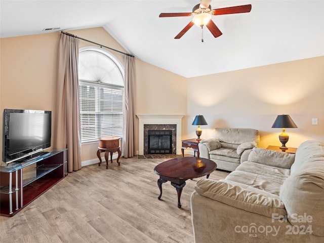 living room with a fireplace, light hardwood / wood-style flooring, vaulted ceiling, and ceiling fan