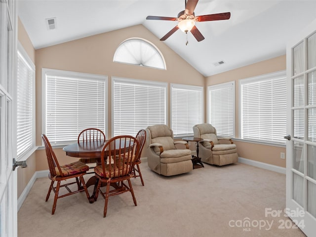 carpeted dining space with ceiling fan and high vaulted ceiling