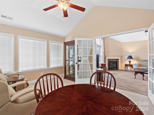 carpeted dining room featuring a fireplace, ceiling fan, french doors, and high vaulted ceiling