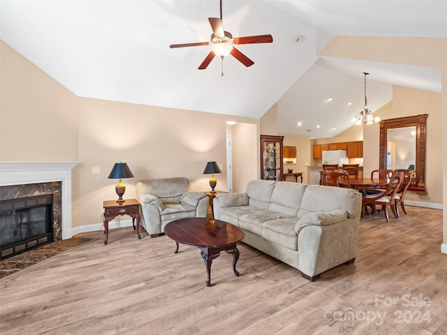 living room featuring a premium fireplace, light hardwood / wood-style flooring, ceiling fan with notable chandelier, and lofted ceiling