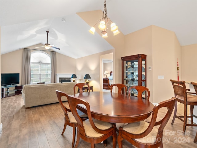 dining area featuring ceiling fan with notable chandelier, lofted ceiling, and light hardwood / wood-style flooring