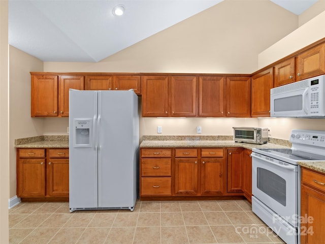 kitchen featuring light stone countertops, light tile patterned floors, and white appliances