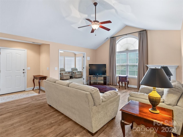 living room featuring ceiling fan, plenty of natural light, light hardwood / wood-style floors, and vaulted ceiling