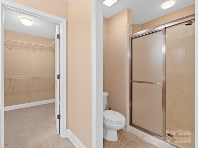 bathroom featuring tile patterned floors, a shower with shower door, and toilet