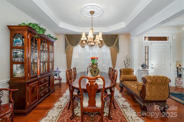 dining space featuring an inviting chandelier, hardwood / wood-style floors, crown molding, and a raised ceiling