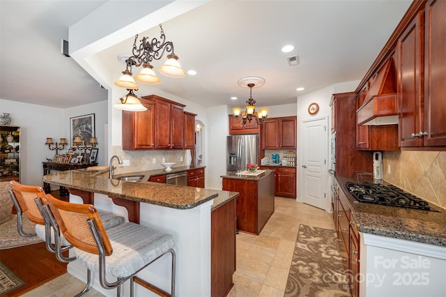 kitchen featuring pendant lighting, sink, appliances with stainless steel finishes, a center island, and kitchen peninsula