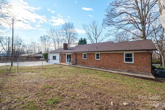 back of house with central AC unit, a patio area, and a lawn