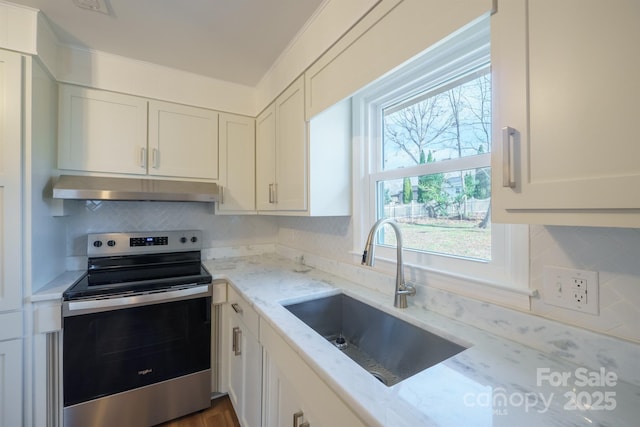 kitchen featuring stainless steel electric stove, white cabinets, sink, light stone countertops, and a healthy amount of sunlight