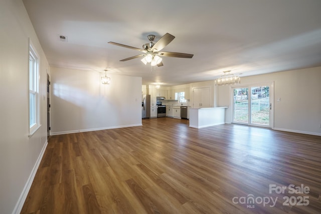 unfurnished living room with wood-type flooring and ceiling fan with notable chandelier