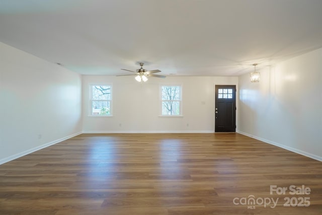 interior space featuring ceiling fan with notable chandelier and dark wood-type flooring