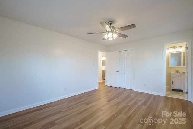 unfurnished bedroom featuring ceiling fan, a closet, light hardwood / wood-style flooring, and ensuite bath