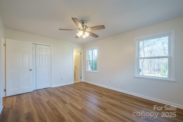 unfurnished bedroom with hardwood / wood-style floors, ceiling fan, multiple windows, and a closet