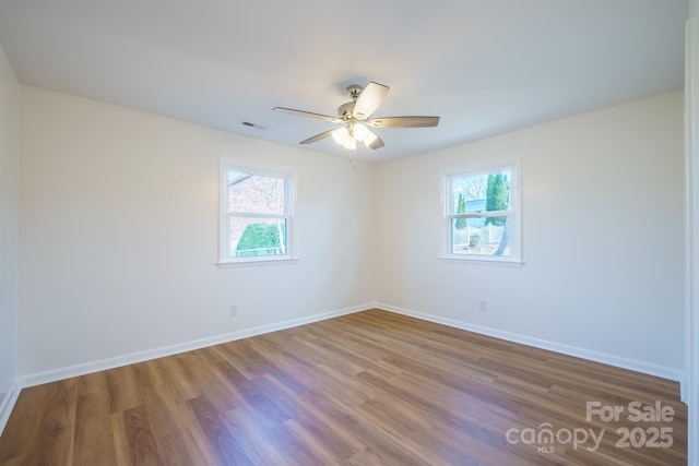 empty room with hardwood / wood-style floors, ceiling fan, and a wealth of natural light