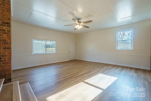 unfurnished room featuring ceiling fan, hardwood / wood-style floors, and a healthy amount of sunlight