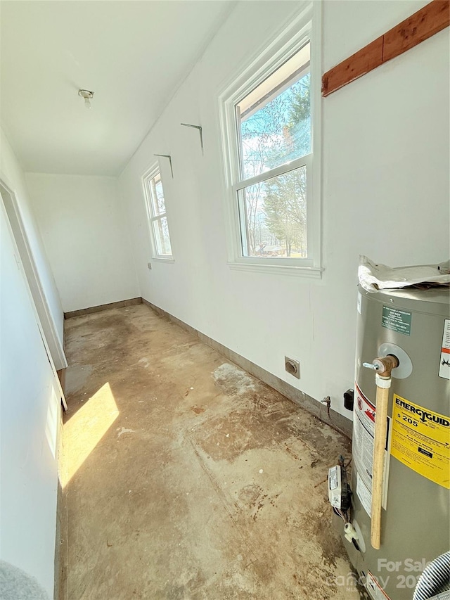 bonus room featuring concrete flooring and gas water heater