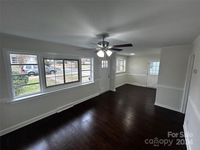 spare room featuring dark hardwood / wood-style floors, ceiling fan, and a healthy amount of sunlight